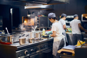 the team of cooks backs in the work in the modern kitchen, the workflow of the restaurant in the kitchen. Copy space for text.